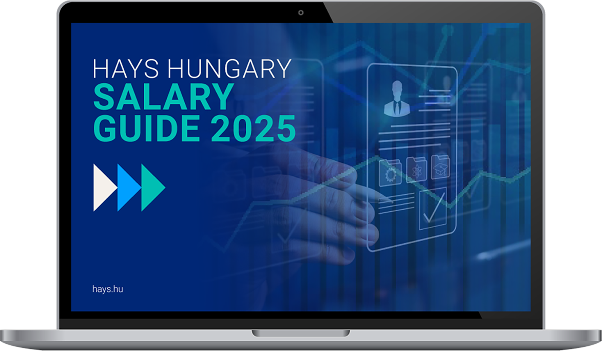 Egy laptop képernyőjén a "Hays Hungary Salary Guide 2025" borító látható, amelyen egy közeli kép van egy kézről, amint épp egy kékszínű, digitális táblára ír, amin adatgrafikonok és felhasználói profilok jelennek meg.